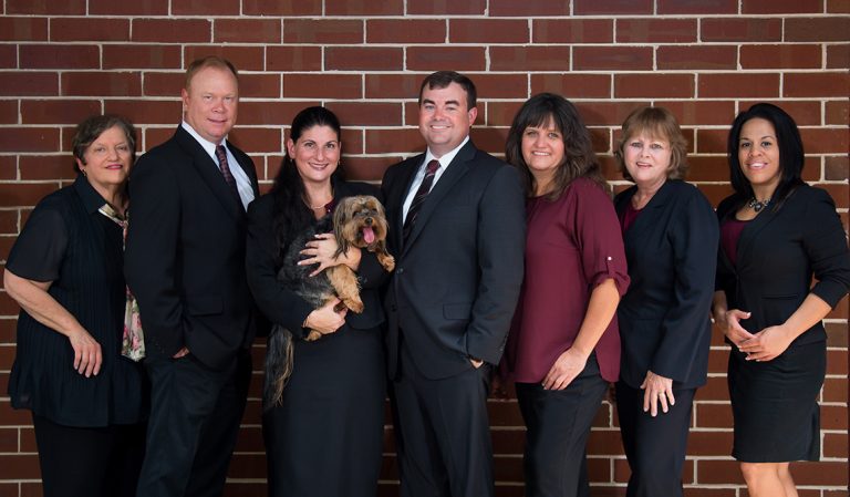 The Schwam-Wilcox & Associates Team Members standing in front of a brick wall